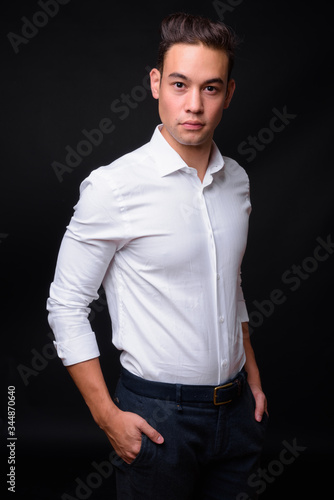 Young handsome multi ethnic businessman against black background © Ranta Images