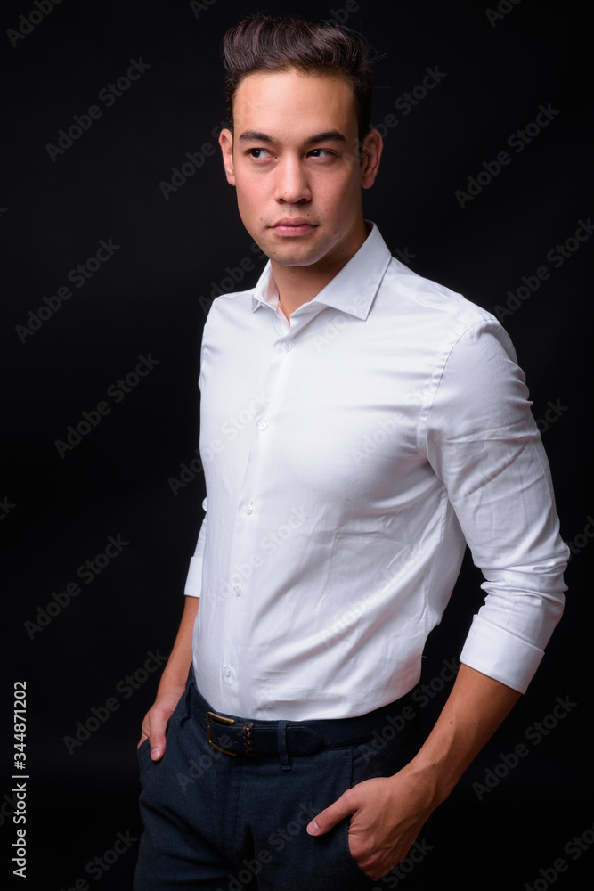 Young handsome multi ethnic businessman against black background Young handsome multi ethnic businessman against black background