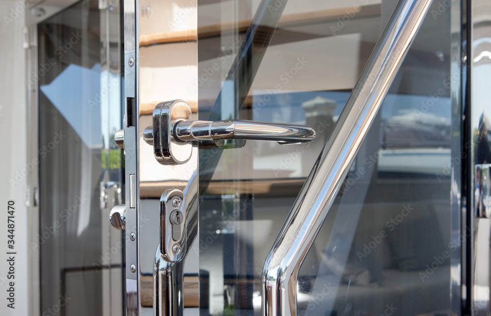 Chrome hinge of a glass door at a luxury yacht. Yachting. Ship building industry.