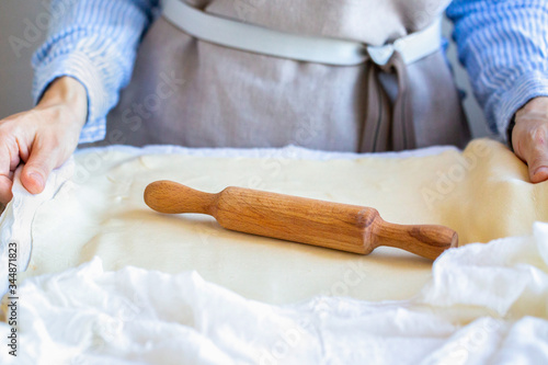 The rolling pin is on the test. The girl rolls the dough with her hands. Cooking pasta. Work with puff pastry at home 