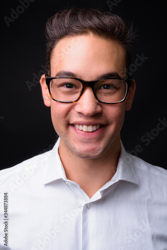 Young handsome multi ethnic businessman against black background