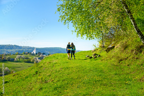 Couple date together in green spring blossom sunny landscape. Rural scenery and church in background. Marriage, family, valentine postcard photo © kovop58