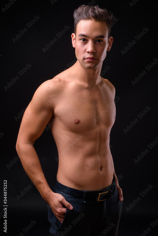 Young handsome multi ethnic man shirtless against black background Young handsome multi ethnic man shirtless against black background