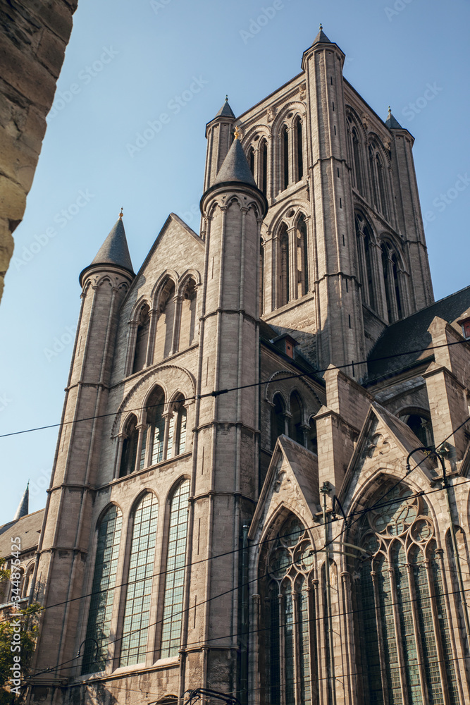 GHENT, BELGIUM - August, 2019: Facade of Saint Nicholas' Church (Sint-Niklaaskerk) with the clock tower of Belfry of Ghent (Het Belfort) at the background, in Ghent. Before before corona crisis