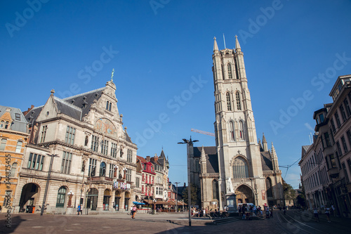 GHENT, BELGIUM - August, 2019: Facade of Saint Nicholas' Church (Sint-Niklaaskerk) with the clock tower of Belfry of Ghent (Het Belfort) at the background, in Ghent. Before before corona crisis