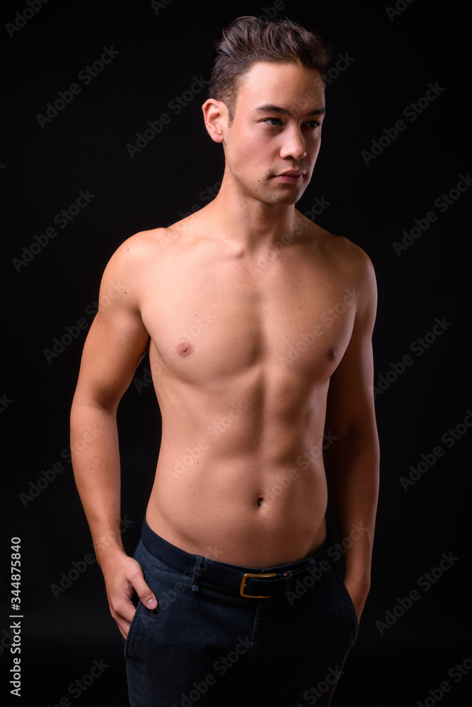 Young handsome multi ethnic man shirtless against black background Young handsome multi ethnic man shirtless against black background