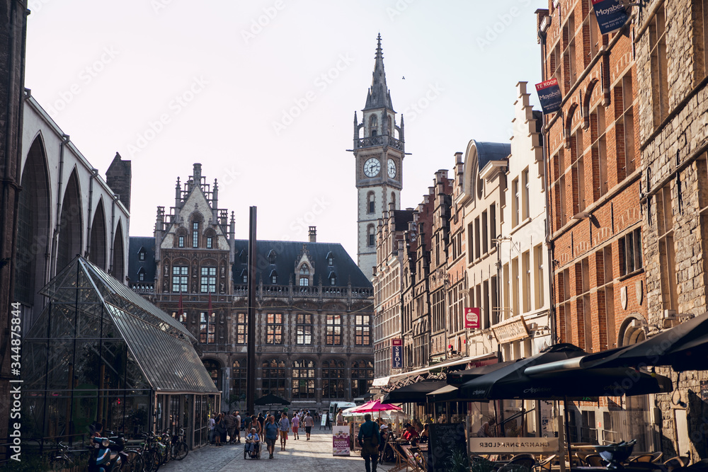 GHENT, BELGIUM - August, 2019: Facade of Saint Nicholas' Church (Sint-Niklaaskerk) with the clock tower of Belfry of Ghent (Het Belfort) at the background, in Ghent. Before before corona crisis