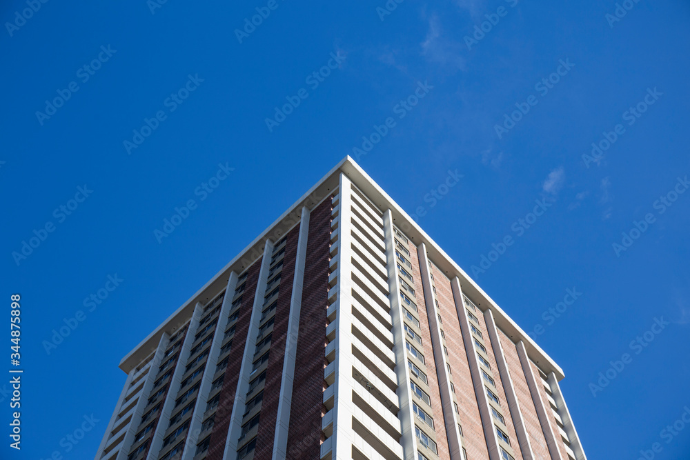 corner of a tall building with multiple square shaped windows seen from below