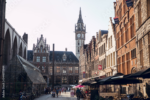 GHENT, BELGIUM - August, 2019: Facade of Saint Nicholas' Church (Sint-Niklaaskerk) with the clock tower of Belfry of Ghent (Het Belfort) at the background, in Ghent. Before before corona crisis © Aitor