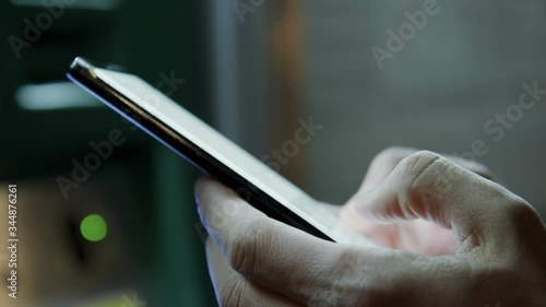 Close-up shot of male two hands texting message on a cell phone at the night city on background. Blurred background and bokeh effects. Handheld . 4K UHD