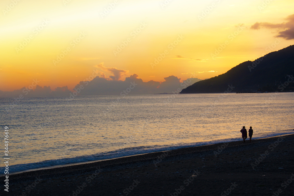 Gorgeous Sunny sunset on the sea with silhouettes of people. Relaxation and peace. The slow life.