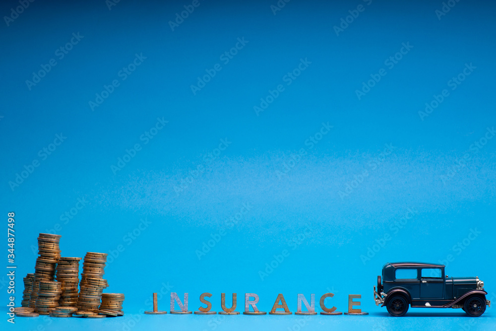 Dark blue car figurine next to some tall columns of coins each with a letter on top together spelling insurance and a large pile of coins, on blue background.