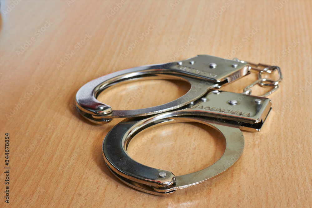 police handcuffs on wooden table police handcuffs on wooden table