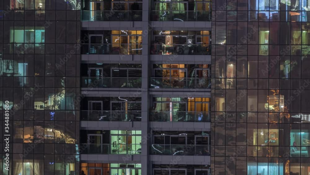Night view of exterior apartment building timelapse. High rise skyscraper with blinking lights in windows with people moving inside. Pan down Night view of exterior apartment building timelapse. High rise skyscraper with blinking lights in windows with people moving inside. Pan down