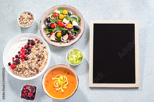 Carrot cream soup, Greek salad, granola bowl with yogurt on concrete table top with copy space. Assortment of dishes for diet, suitable for volumetrics diet and other nutrition strategies, top view