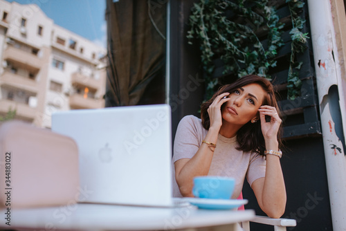 Beautiful young caucasian woman with phone and laptop in cafe