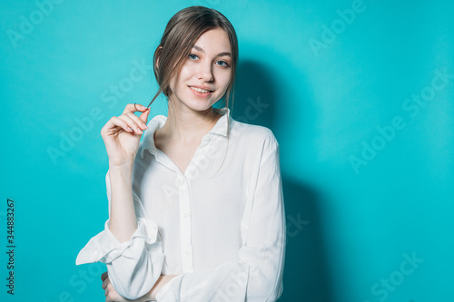 young girl in a white shirt and jeans with a laptop on a blue background in the studio