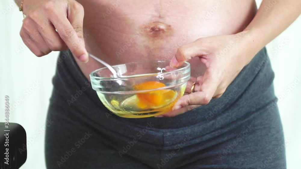 Slow motion hands of pregnant woman use cutlery cracking an egg into a bowl with standing by in kitchen. Mother pregnant cooking meal fried omelettes in kitchen. Slow motion hands of pregnant woman use cutlery cracking an egg into a bowl with standing by in kitchen. Mother pregnant cooking meal fried omelettes in kitchen.