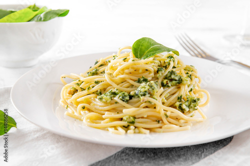  spaghetti , pasta with spinach and cheese on a plate , fresh spinach leaves,