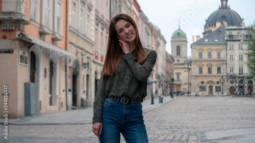 Close up portrait of a beautiful smiling girl with brown hair. Urban city background © Rudchyks