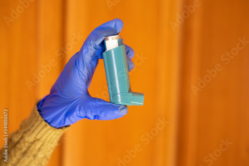 Gloved hands holding an asthma inhaler. photo