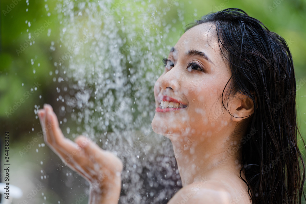 Obraz premium Asian woman, she uses a shower and wash hair outside. She is resting at the resort.