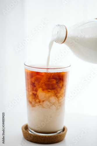 pouring milk into a black tea glass