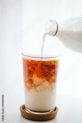 pouring milk into a black tea glass