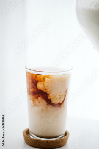 Black tea combining with milk in a glass mug