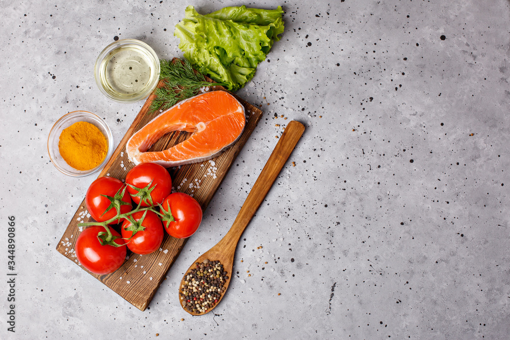 Salmon fillet with spices and vegetables on a grey background. Culinary education. Food background. Healthy food balance. Salmon steak, raw fish cooked for cooking. on a gray background .Top view Salmon fillet with spices and vegetables on a grey background. Culinary education. Food background. Healthy food balance. Salmon steak, raw fish cooked for cooking. on a gray background .Top view