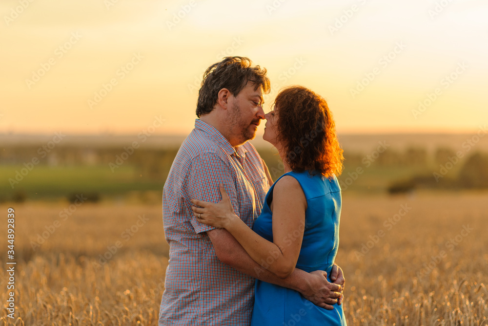 Adult farmer and wife spend time in the field. A moment before the kiss. Adult farmer and wife spend time in the field. A moment before the kiss.