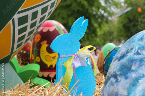 A big blue rabbit sits near a vase with Easter eggs. blue decorative Easter bunny near the big eggs. Holiday composition. photo