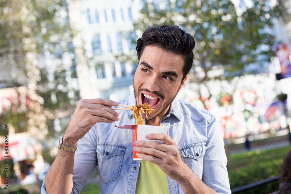 Fototapeta premium Man eating noodles outdoors
