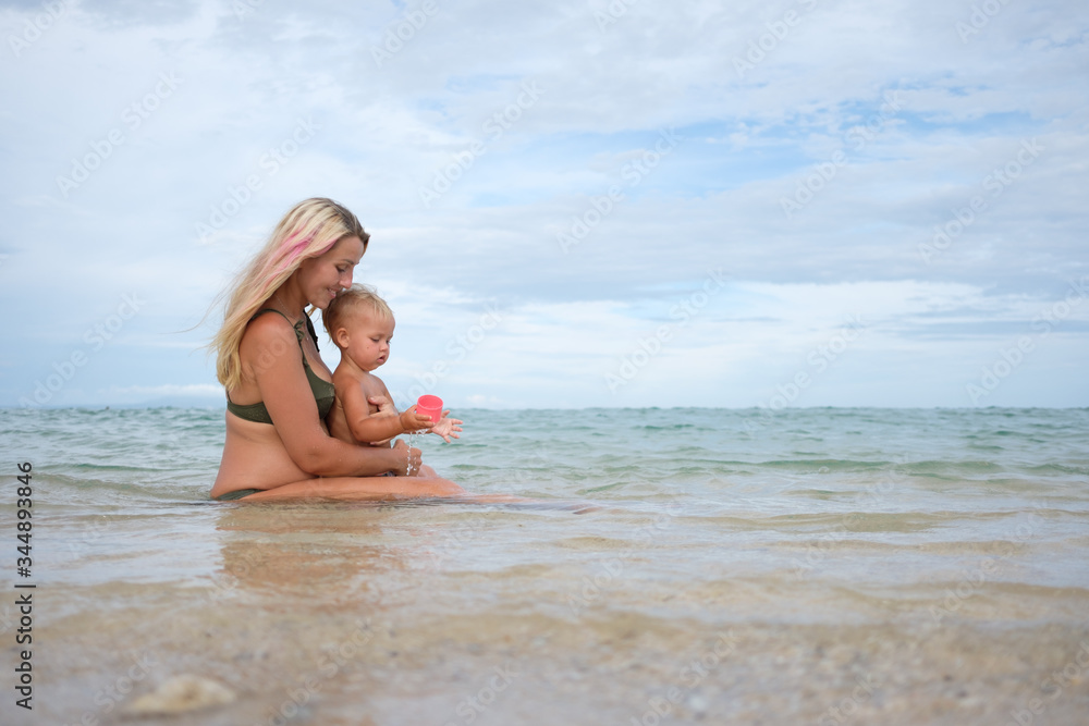 Panorama of happy beautiful mother with daughter walking together on tropical beach during summer vacation