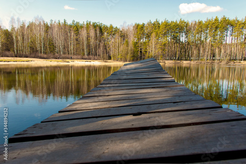 wooden bridge on the lake above the water against the background of the forest