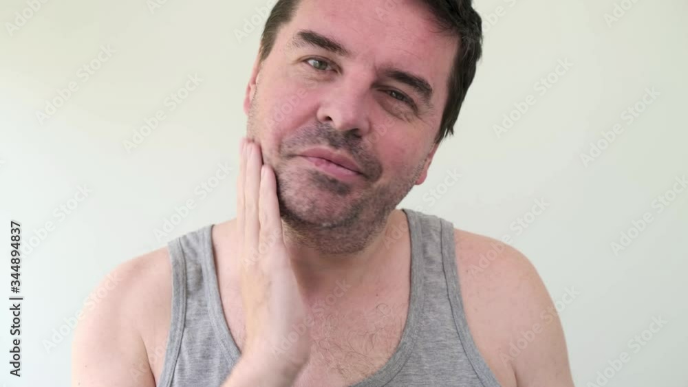 Happy Handsome 40 years old middle aged bearded man apply skincare cream on face, looking at camera.. Healthy skin care treatment, male beauty concept. Happy Handsome 40 years old middle aged bearded man apply skincare cream on face, looking at camera.. Healthy skin care treatment, male beauty concept.