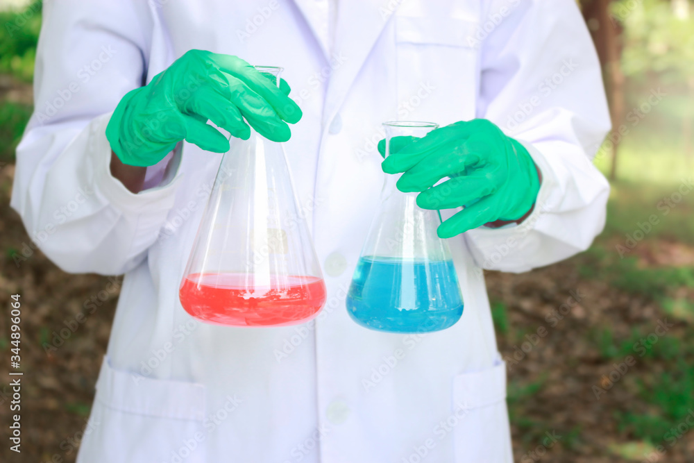 Scientist doing science experiment surround green nature park garden, researcher woman hand holding conical flask with chemical solutions, green chemical and environmental friendly science concept Scientist doing science experiment surround green nature park garden, researcher woman hand holding conical flask with chemical solutions, green chemical and environmental friendly science concept