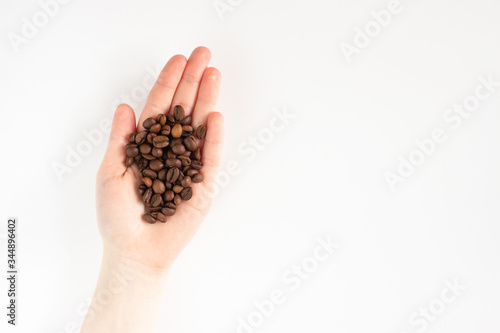 Roasted coffee beans in female hand isolated on white background top view with copy space. Aroma drink. Web banner template. Stock photo.