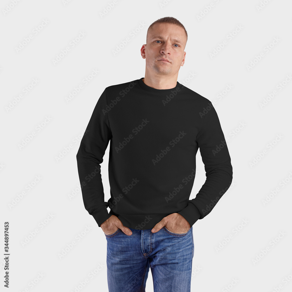 Fototapeta premium Template of black blank sweatshirt on a man in blue jeans with hands in pockets, textile heather isolated on a white background.