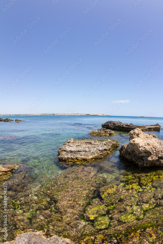 Panorama of the wild nature, blue crystal water of Mediterranean sea and rocky coastline at sunset in province Syracuse in Sicily