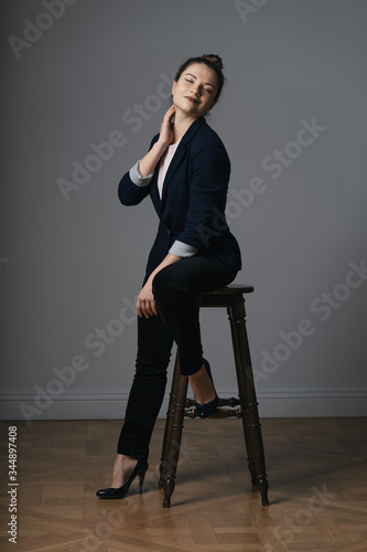 Portrait of a beautiful young business woman standing against grey wall