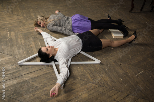 Triller film. Two women lie on the floor near the pentagram. photo