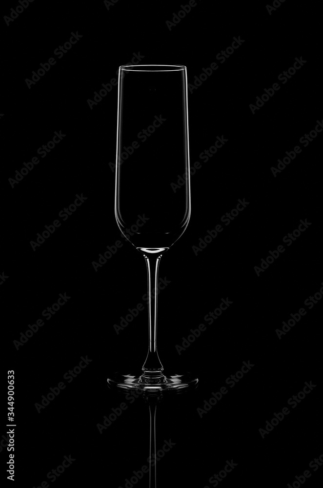 a glass champagne glass stands on a black background