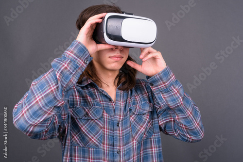 Young handsome hipster man with long hair using virtual reality headset