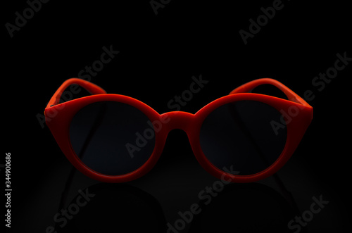Red sunglasses lie on a black background