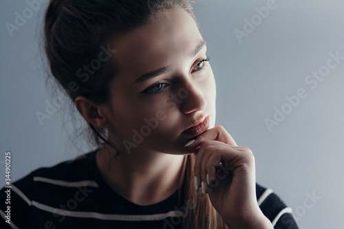 portrait of a beautiful pensive girl with makeup on gray studio isolated background, cyoung woman thinking, concept beauty and life photo