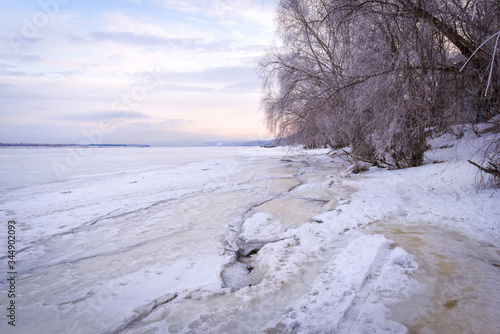 Winter landscape at dawn, riverbank of a frozen ice.