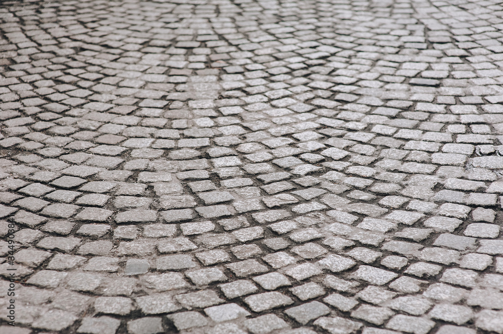 The dark gray paving stones laid out in a semicircle. The texture of the old granite stone. Road surface. Vintage and grunge.