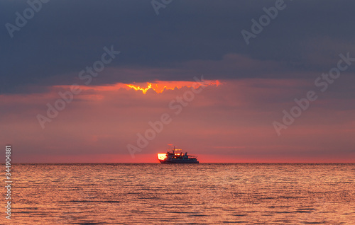 A ship at sea caught the sun. Sea sunset.