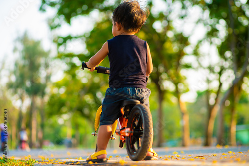 Fototapeta Naklejka Na Ścianę i Meble -  Adorable little boy exercise with balance bike in city park